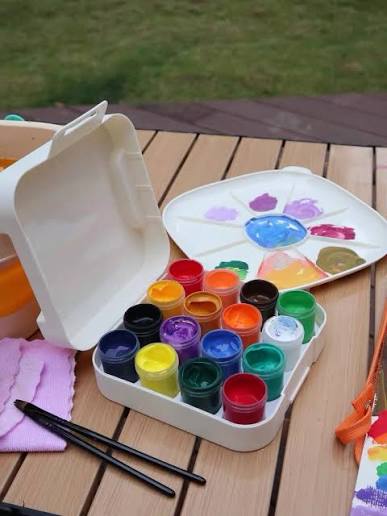 Gouache paint tubes, brushes and vivid matte color swatches arranged on artist paper
